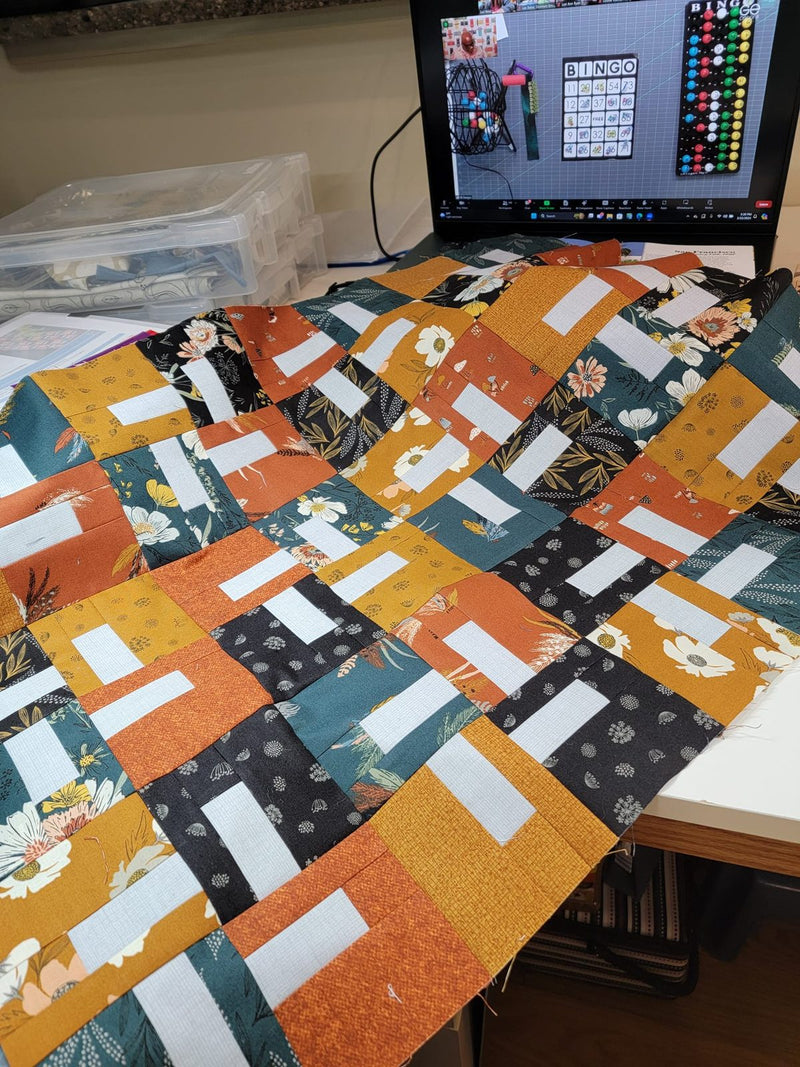 Quilt blocks in progress, with the retreat bingo board on the screen behind