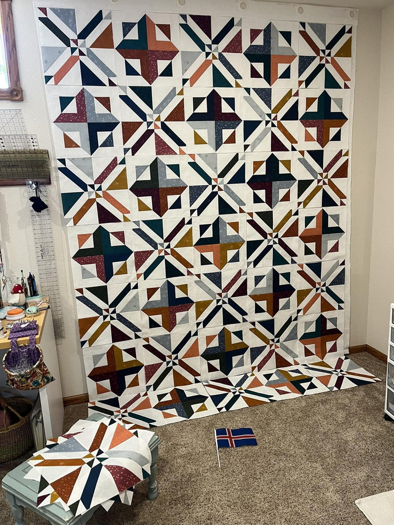 A star-pattern quilt top on a design wall in a sewing room